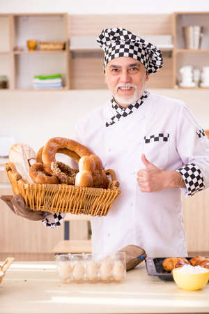 Old male baker working in the kitchen