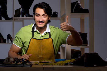 Young shoemaker in workshop at night