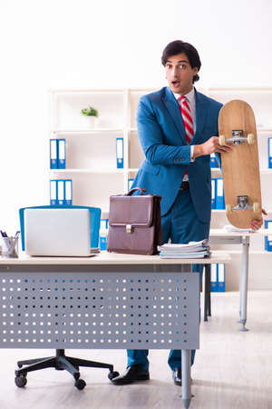 Young handsome businessman with longboard in the officeの写真素材