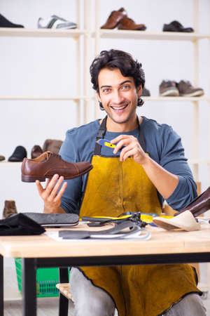 Young man repairing shoes in workshopの写真素材
