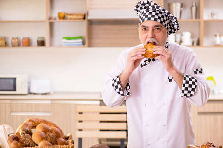 Old male baker working in the kitchen