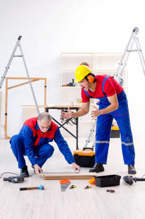 Two professional contractors laying flooring at homeの写真素材