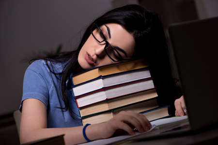 Young female student preparing for exams at night time
