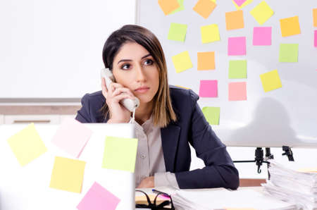 Young female employee in conflicting priorities conceptの写真素材