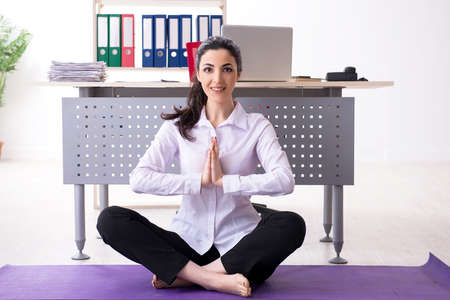 Young female employee doing exercises in the officeの写真素材