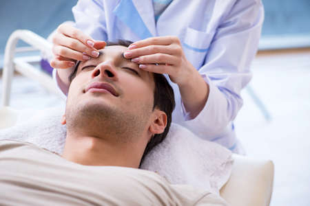 Young handsome man visiting female doctor cosmetologistの写真素材