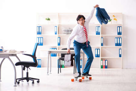 Young handsome businessman with longboard in the officeの写真素材