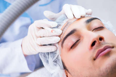 Young handsome man visiting female doctor cosmetologistの写真素材