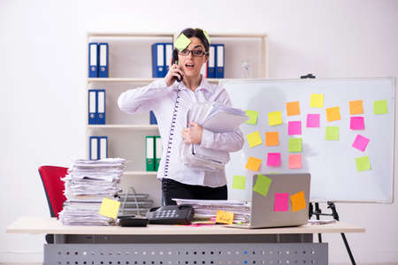 Young female employee in conflicting priorities conceptの写真素材