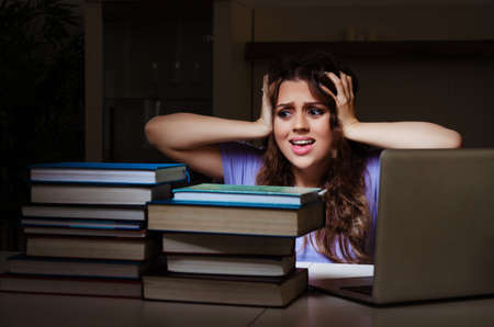 Young female student preparing for exams late at homeの写真素材