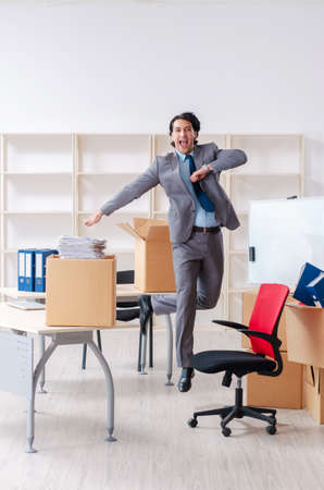 Young man employee with boxes in the officeの写真素材