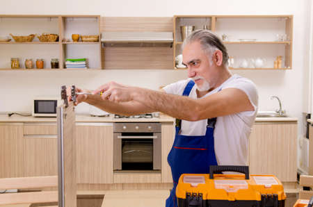 Aged contractor repairman working in the kitchenの写真素材
