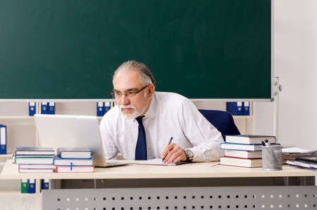 Aged male teacher in front of chalkboardの写真素材