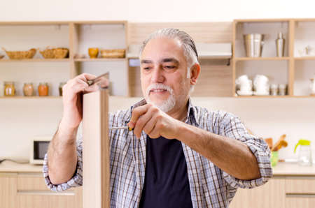 Aged contractor repairman working in the kitchenの写真素材