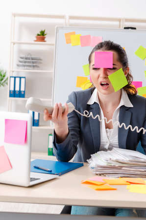 Young female employee in conflicting priorities conceptの写真素材