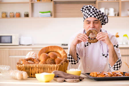 Old male baker working in the kitchen