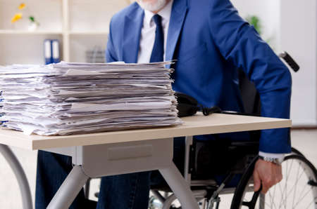Aged employee in wheelchair working in the office