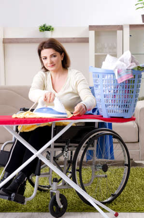 Woman in wheelchair ironing at homeの写真素材