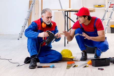 Two professional contractors laying flooring at homeの写真素材