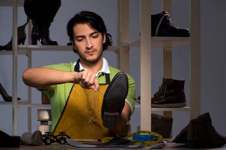 Young shoemaker in workshop at night