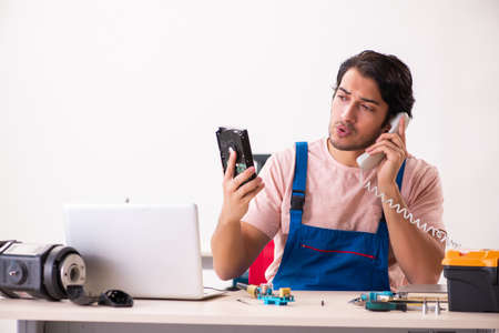 Young male contractor repairing computerの写真素材