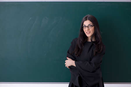 Female graduate student in front of green board