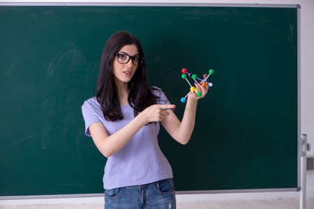 Young female teacher student in front of green board