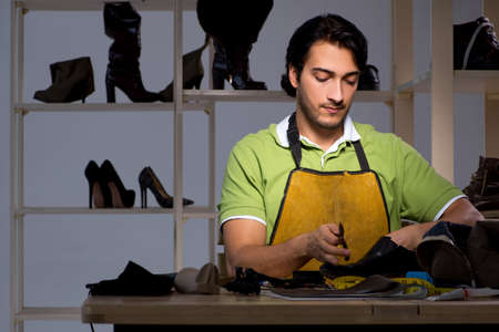 Young shoemaker in workshop at night