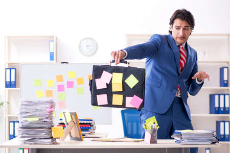 Young male handsome employee in conflicting priorities conceptの写真素材