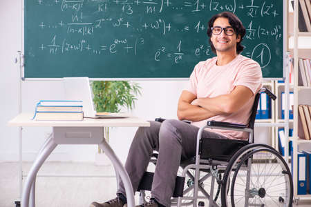 Young handsome man in wheelchair in front of chalkboardの写真素材