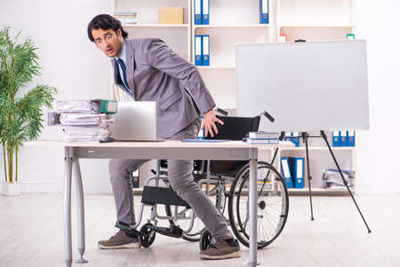 Young handsome employee in wheelchair at the officeの写真素材