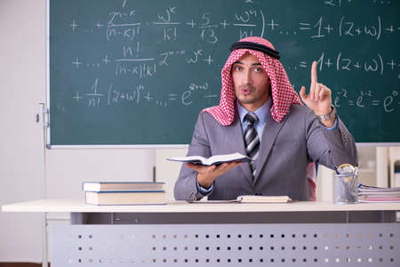 Arab teacher wearing suit in front of chalkboardの写真素材