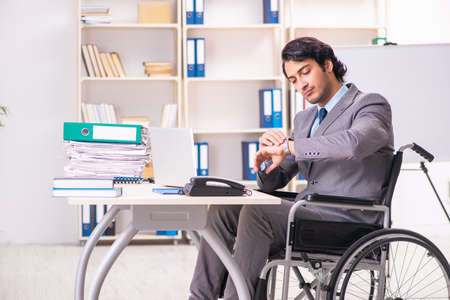 Young handsome employee in wheelchair at the officeの写真素材