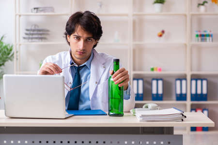 Young male doctor drinking in the officeの写真素材