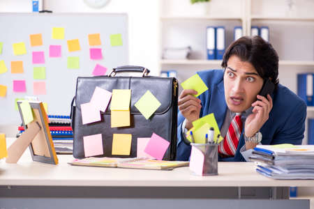 Young male handsome employee in conflicting priorities conceptの写真素材