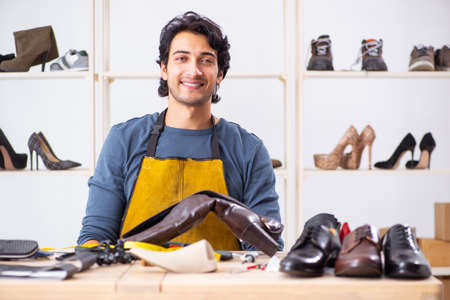 Young man repairing shoes in workshop