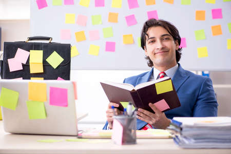 Young male handsome employee in conflicting priorities conceptの写真素材