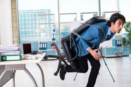 Chained male employee unhappy with excessive workの写真素材