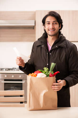 Young handsome man with vegetables in the kitchenの写真素材