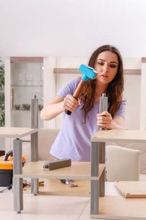 Young woman repairing chair at homeの写真素材