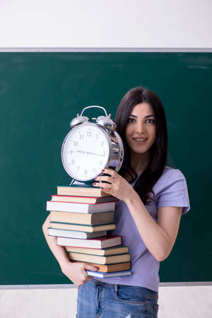 Young female teacher student in front of green boardの写真素材