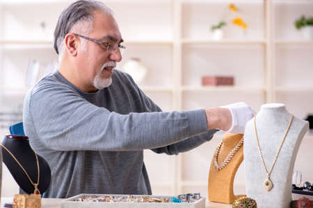 White bearded old jeweler at workshopの写真素材