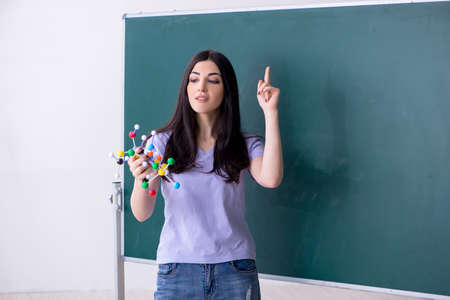 Young female teacher student in front of green board