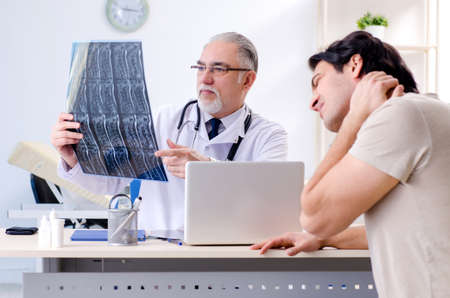 Young man visiting old male doctor radiologistの写真素材