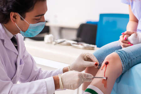 Leg injured young woman visiting male doctorの写真素材