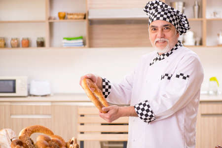 Old male baker working in the kitchen
