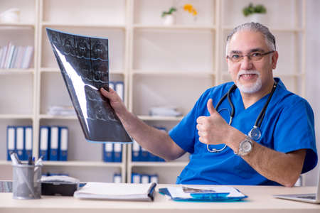 White bearded old doctor radiologist working in clinic