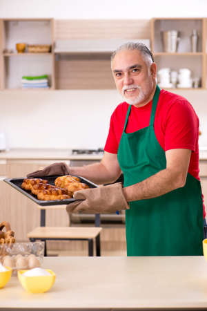Old male baker working in the kitchenの写真素材