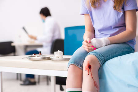 Leg injured young woman visiting male doctorの写真素材