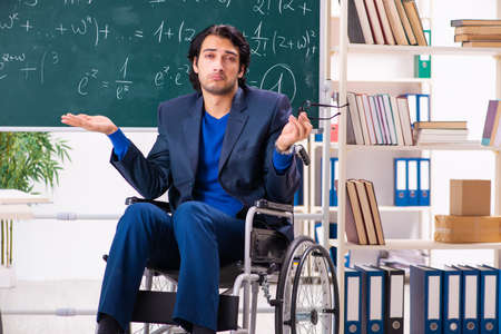 Young handsome man in wheelchair in front of chalkboardの写真素材